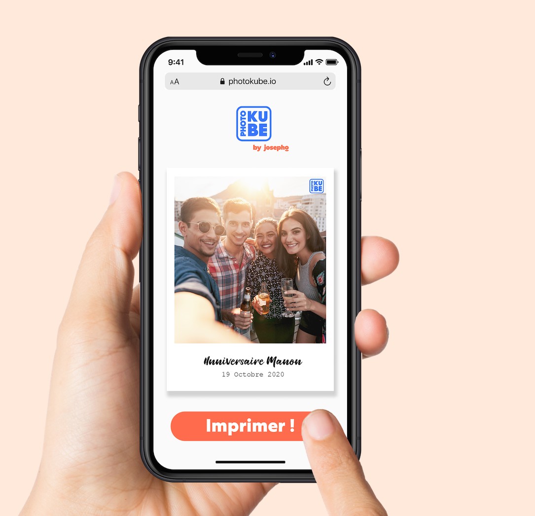 Une main tient un téléphone portable pour choisir la photo qu'elle veut imprimer à distance sur le PhotoKube